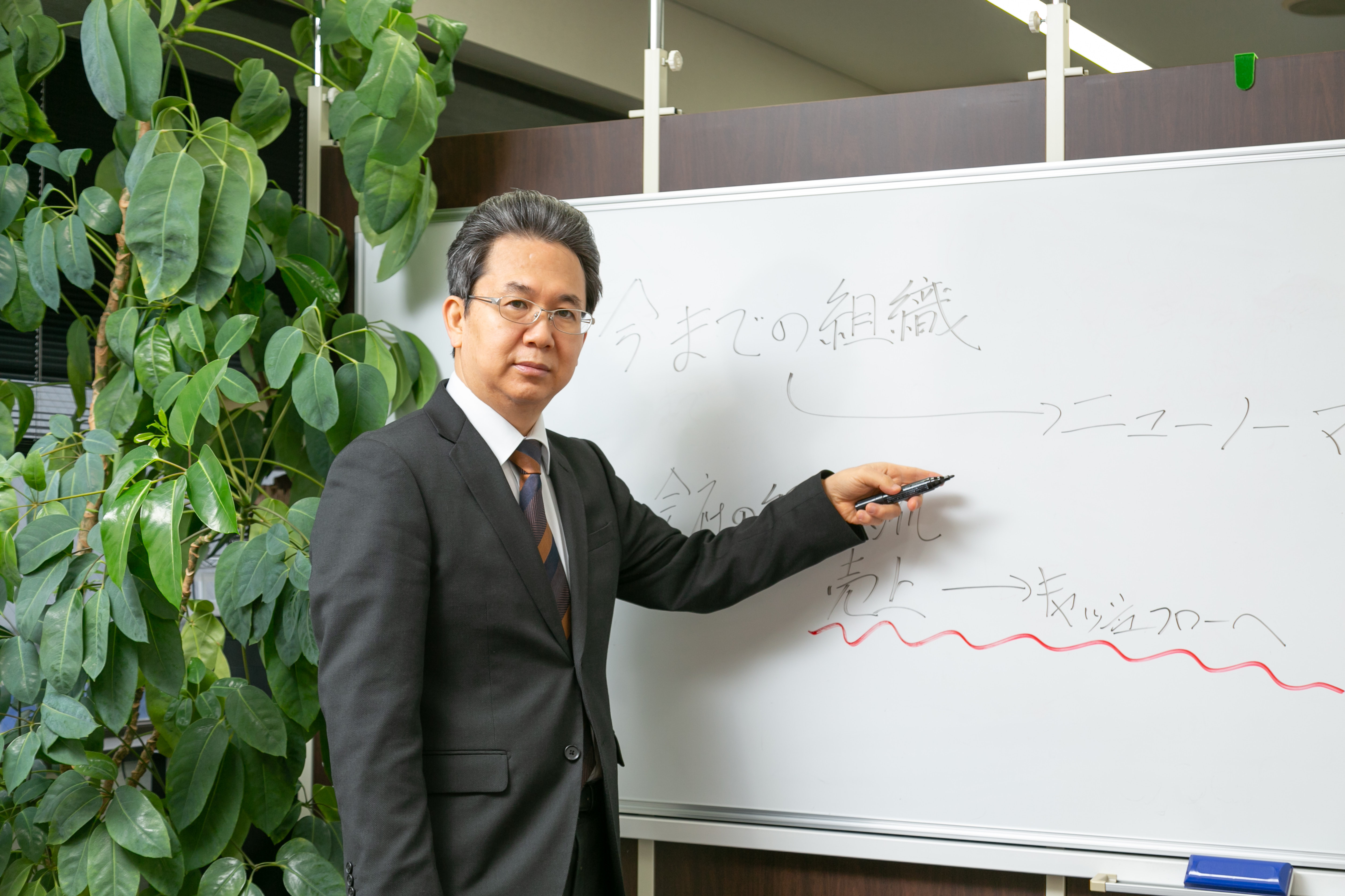 ホワイトボードに組織の図を書きながら解説する川原一紀さん