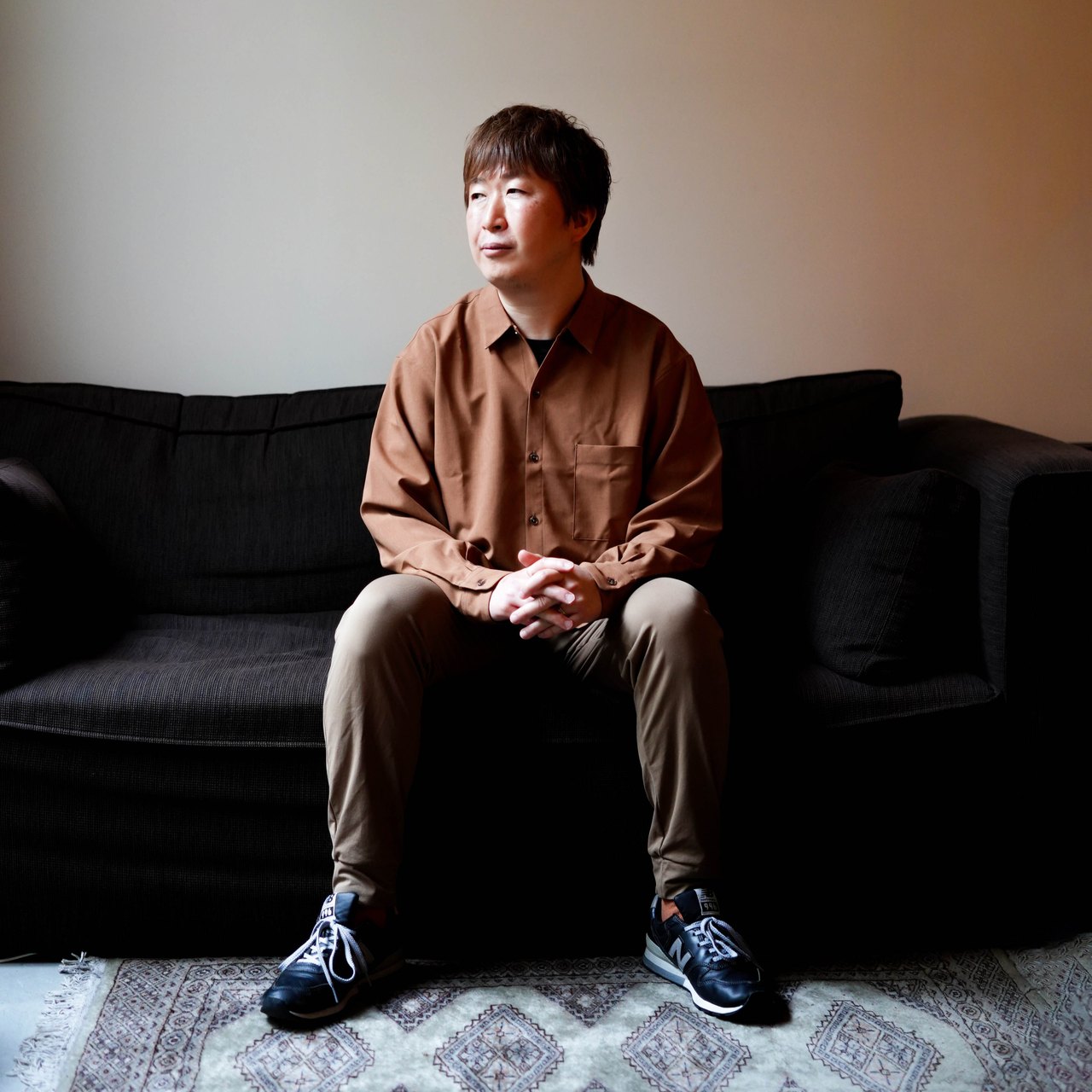ソファに腰かけ、手を組んで前方を見つめる岡田商会の岡山耕二郎氏