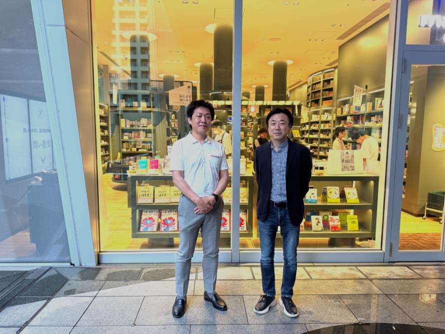 書店の前に並ぶ河村裕司さんと支援先の経営者